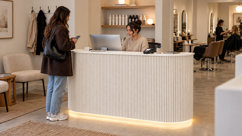 Receptionist helping a client at a Lurpes reception counter in a working salon