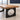 Thick light-brown wood rectangular table with two black slab supports, each with a circular cutout visible material detail in the same office