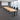 Lurpes oak conference table with five black support frames and four cable lids in a gray boardroom, elevated camera view