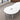 White double-rounded waisted meeting table with two cable ports and three silver supports, visible surface detail in the same office